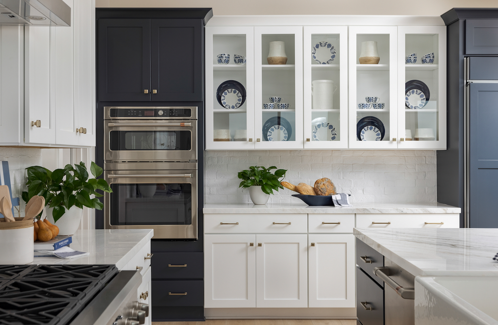 Traditional kitchen featuring both white and dark blue cabinets, white marbled countertops and Creative Mines Brewery Paintgrade Brick as the backsplash painted in white.