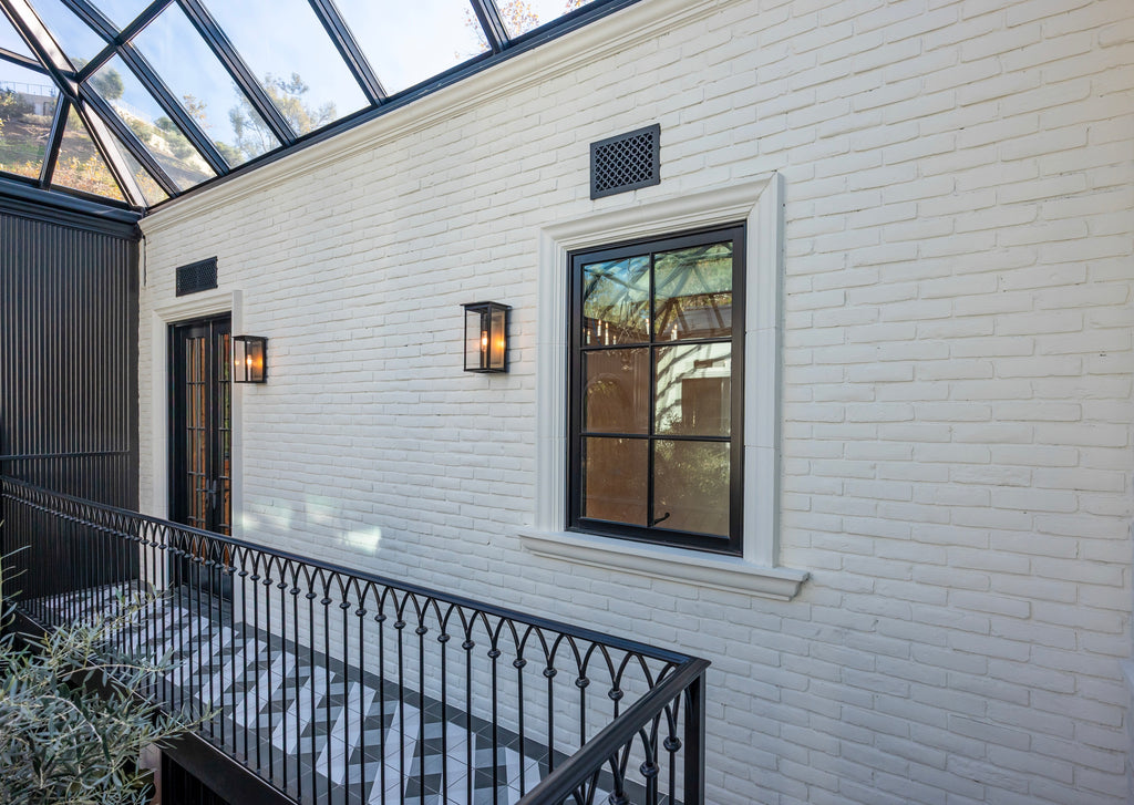 Interior balcony sunroom featuring iron railing and Creative Mines wall of Loft Paintgrade Brick Veneer painted in white.