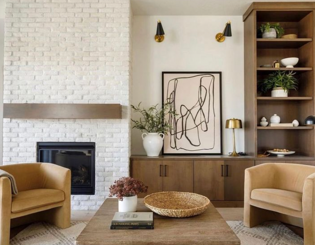 Living room featuring earth tone chairs, wood coffee table and Creative Mines Loft Paintgrade Brick Veneer Fireplace Wall painted in white.